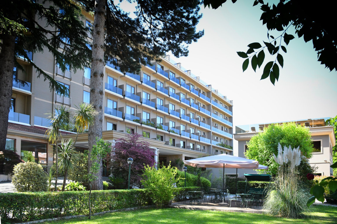 Hotel-e-giardino-con-ombrelloni-tavoli-sedie-apparecchiato-per-pranzi-all-aperto-aperitivi-cene-in-giardino-garden-lunch-happy-our-aperitif-appetizer-light-lunch-dinner-tree-plant-grass-hotel-san-giorgio-heaven-spa